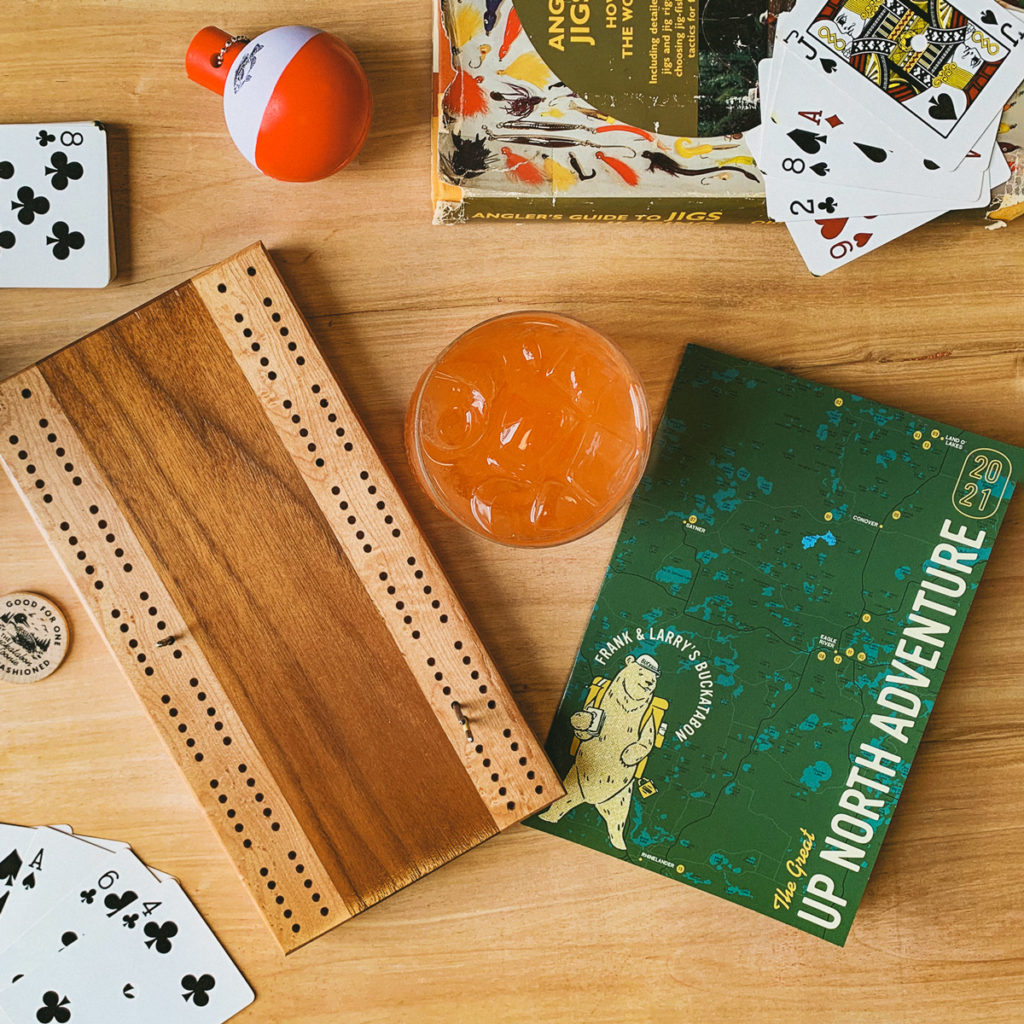 Buckatabon's 2021 Up North Adventure Passport along with a game of cribbage and an Old Fashioned