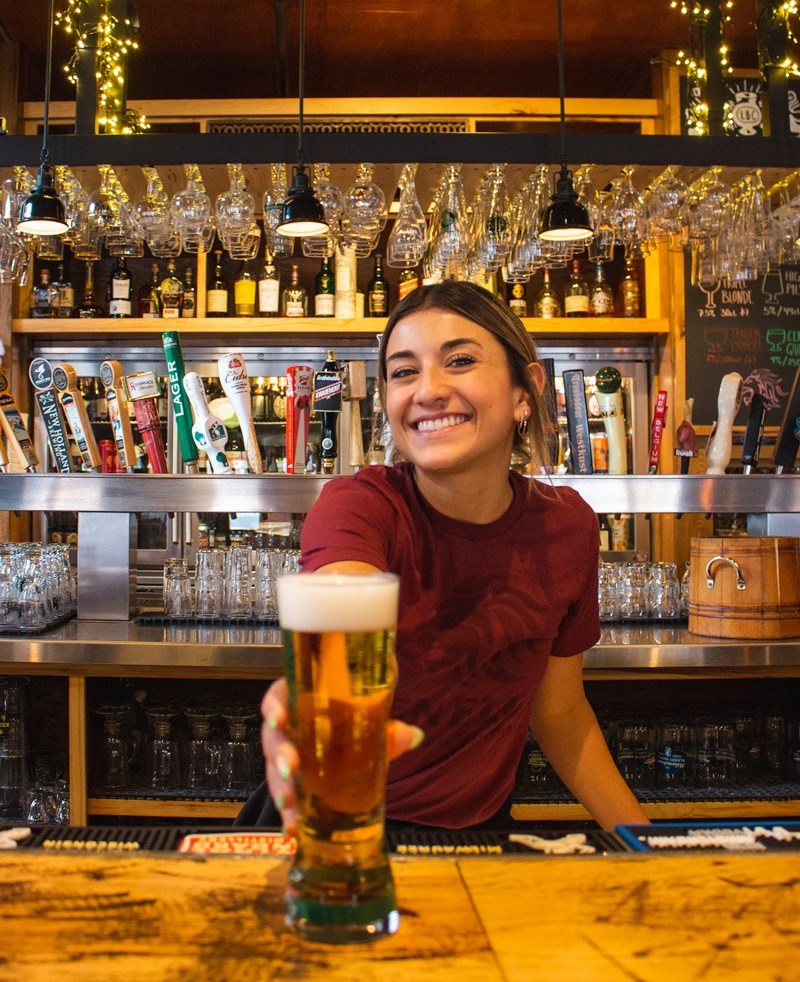 Server presenting a full beer with a smile on her face
